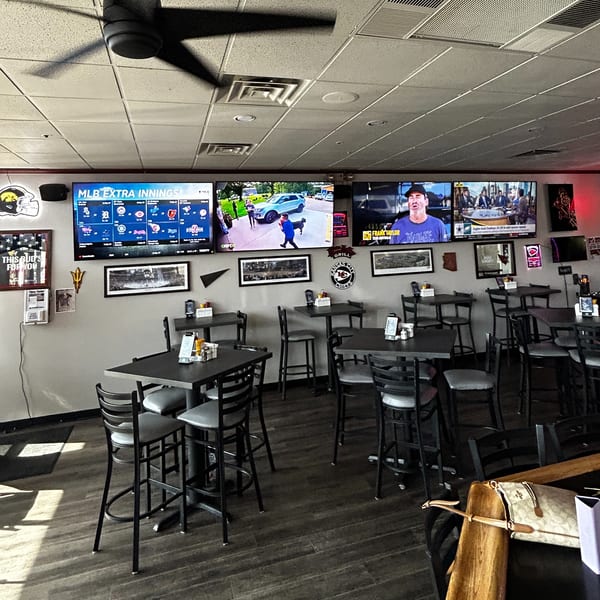 Interior of Moon Valley Grill & Patio with multiple TVs showing sports, high-top tables, and bar stools.