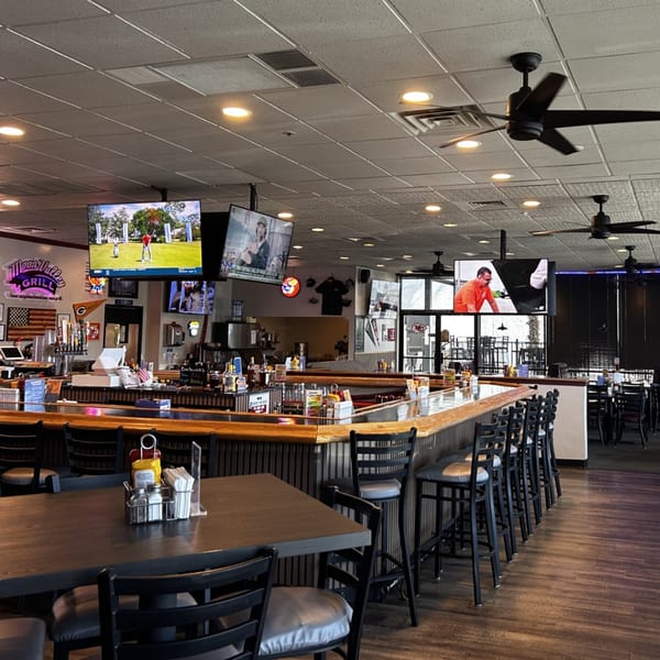 Interior of Moon Valley Grill & Patio, featuring a long bar with stools, tables, and multiple TVs.