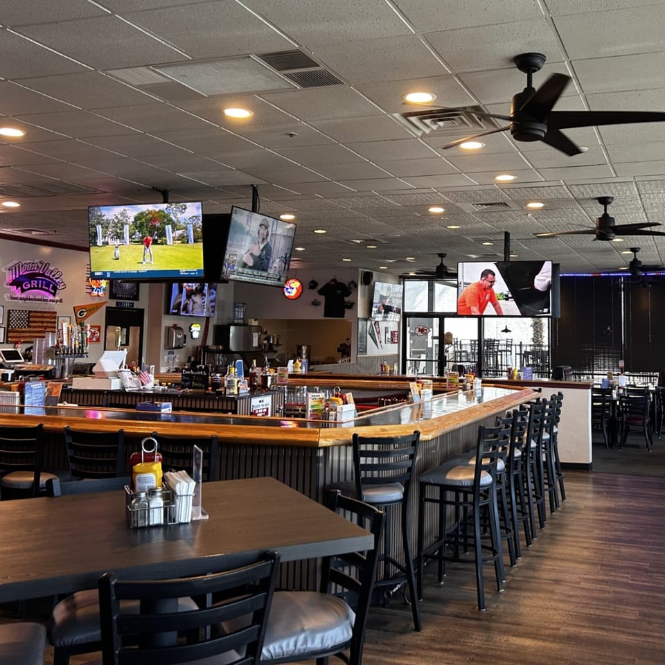 Interior of Moon Valley Grill & Patio, featuring a long bar with stools, tables, and multiple TVs.