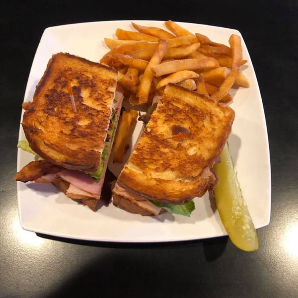 Moon Valley Grill & Patio's grilled sandwich with fries and a pickle spear on a white plate.