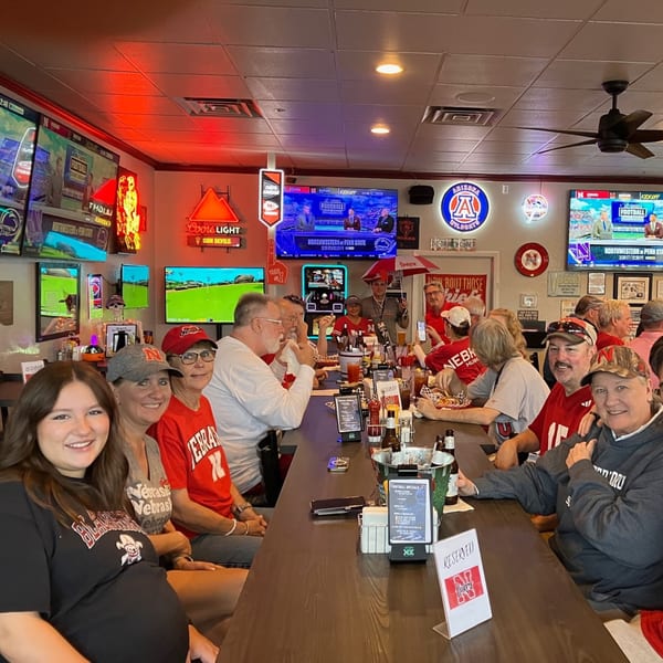 Patrons in red shirts and hats watch football on multiple screens at Moon Valley Grill & Patio.