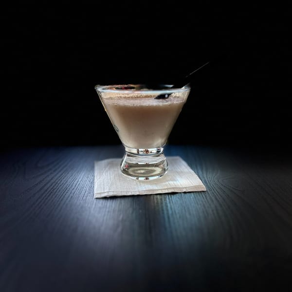 A creamy Moon Valley Grill & Patio cocktail in a martini glass with a dark straw on a napkin.
