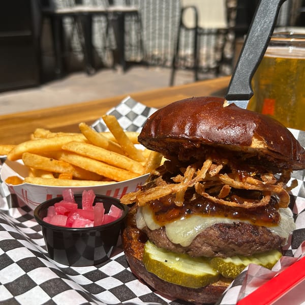 Moon Valley Grill & Patio burger with fries, pickled onions, and a beer on a patio table.